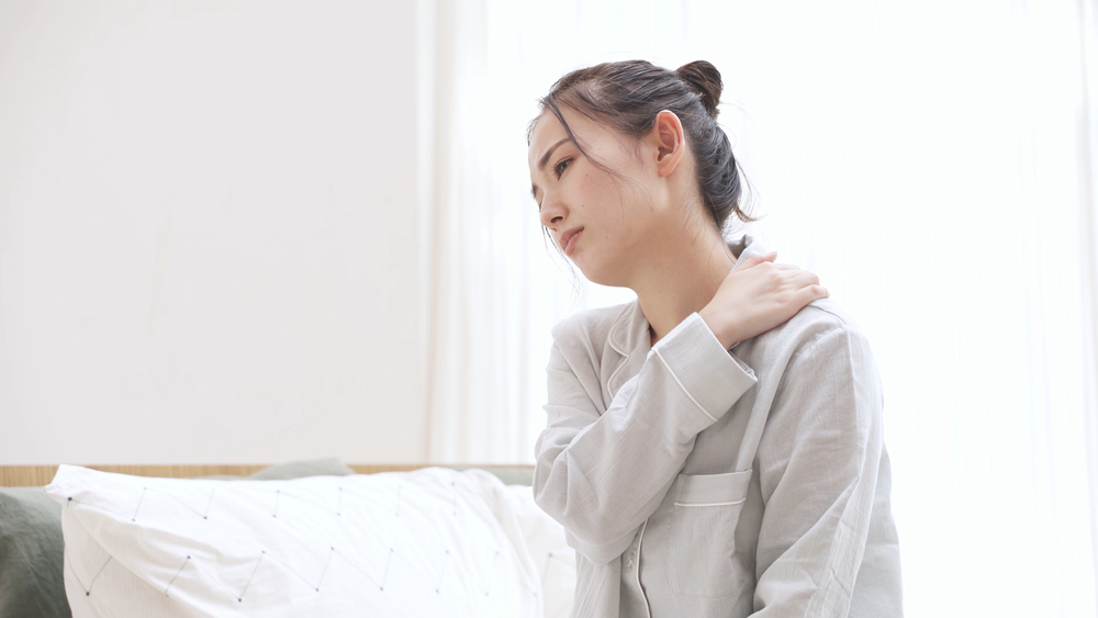 朝起きて肩がこっていることに気づいた女性
