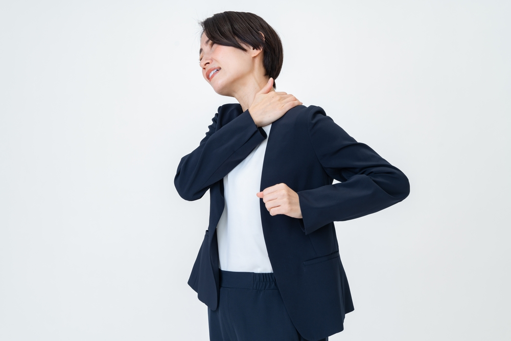 左肩のトリガーポイントを気にしているスーツの女性