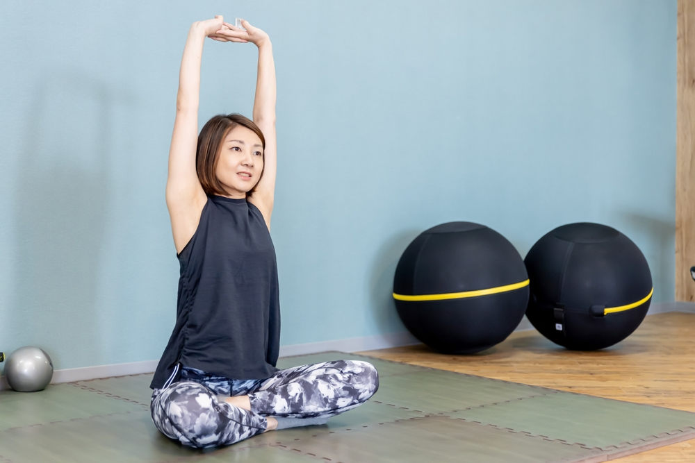 座って腕を上げてストレッチをする女性