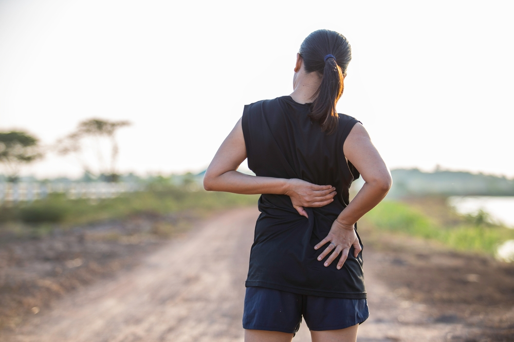 運動中に腰痛で足を止めている女性