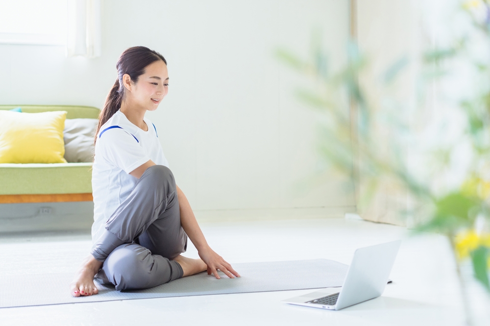 ヨガマット上でストレッチする女性