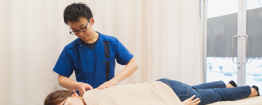 肩甲骨付近の施術をおこなう整体師
