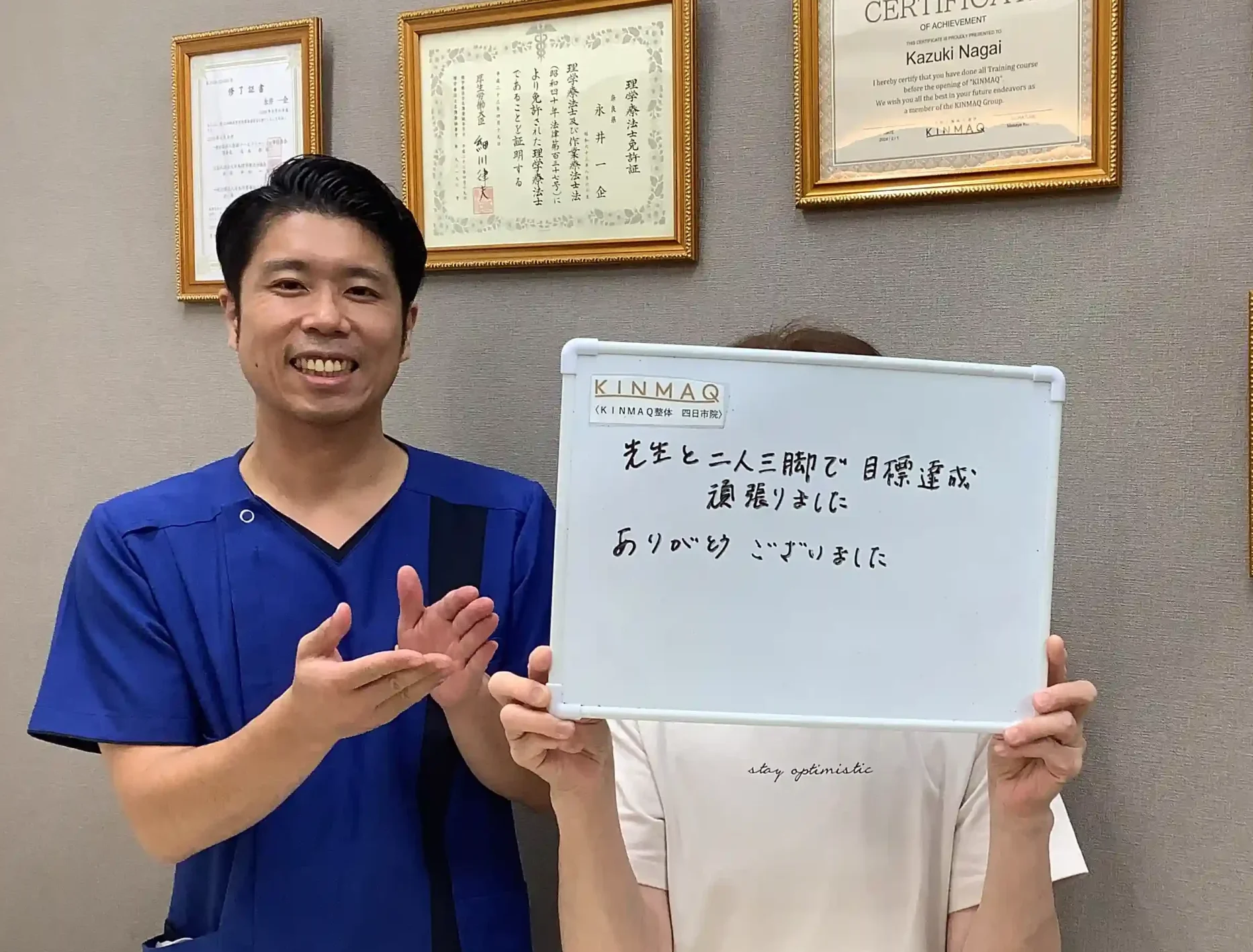 四日市の整体院で股関節の痛みの改善のために通院していたお客様の改善実績として。施術後のご本人が『先生と二人三脚で目標達成頑張りました　ありがとうございました』と書いたホワイトボードを持ち、担当した理学療法士と2ショットを撮影したときの写真。