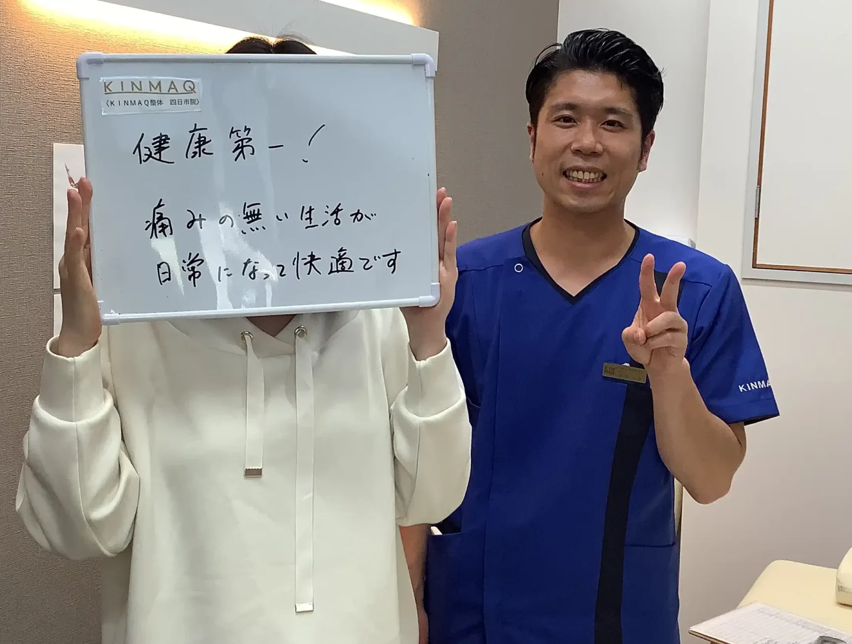 四日市の整体院で股関節の痛みで通院していた女性の改善実績として。施術後のご本人が『健康第一！痛みのない生活が日常になって快適です』と記入したホワイトボードを持ち担当する理学療法士と2ショットを撮影したときの写真。