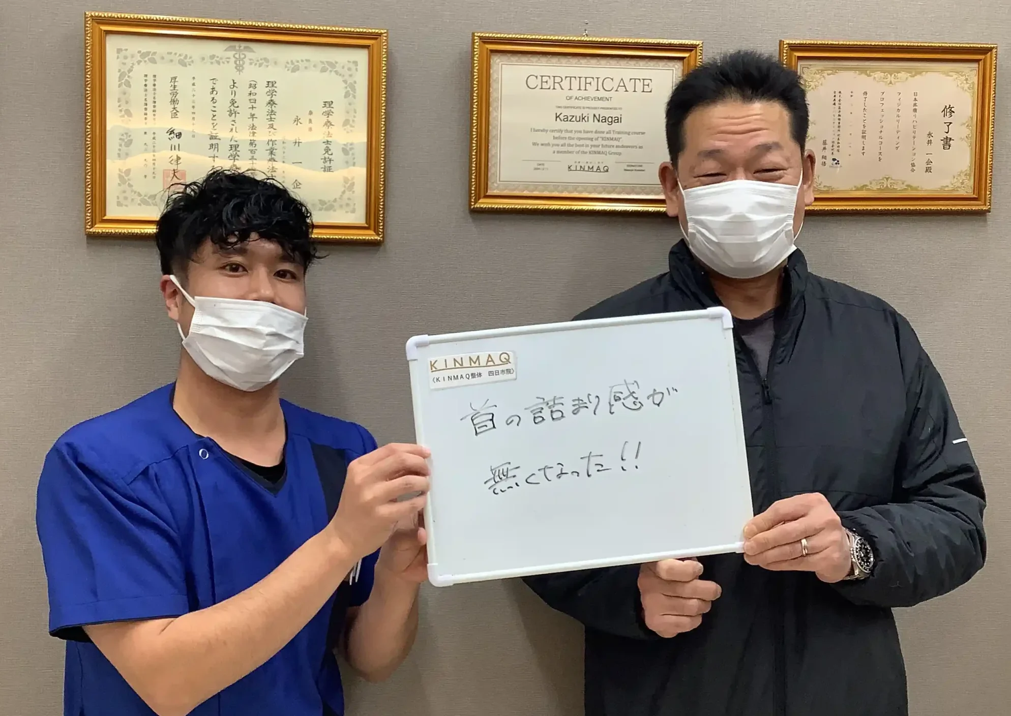 四日市の整体院で首の痛みの改善のために通院していた男性の改善実績として。施術後にご本人が『首の詰まり感が無くなった！！』と書いたホワイトボードを持ち、担当した理学療法士と2ショットを撮影したときの写真。