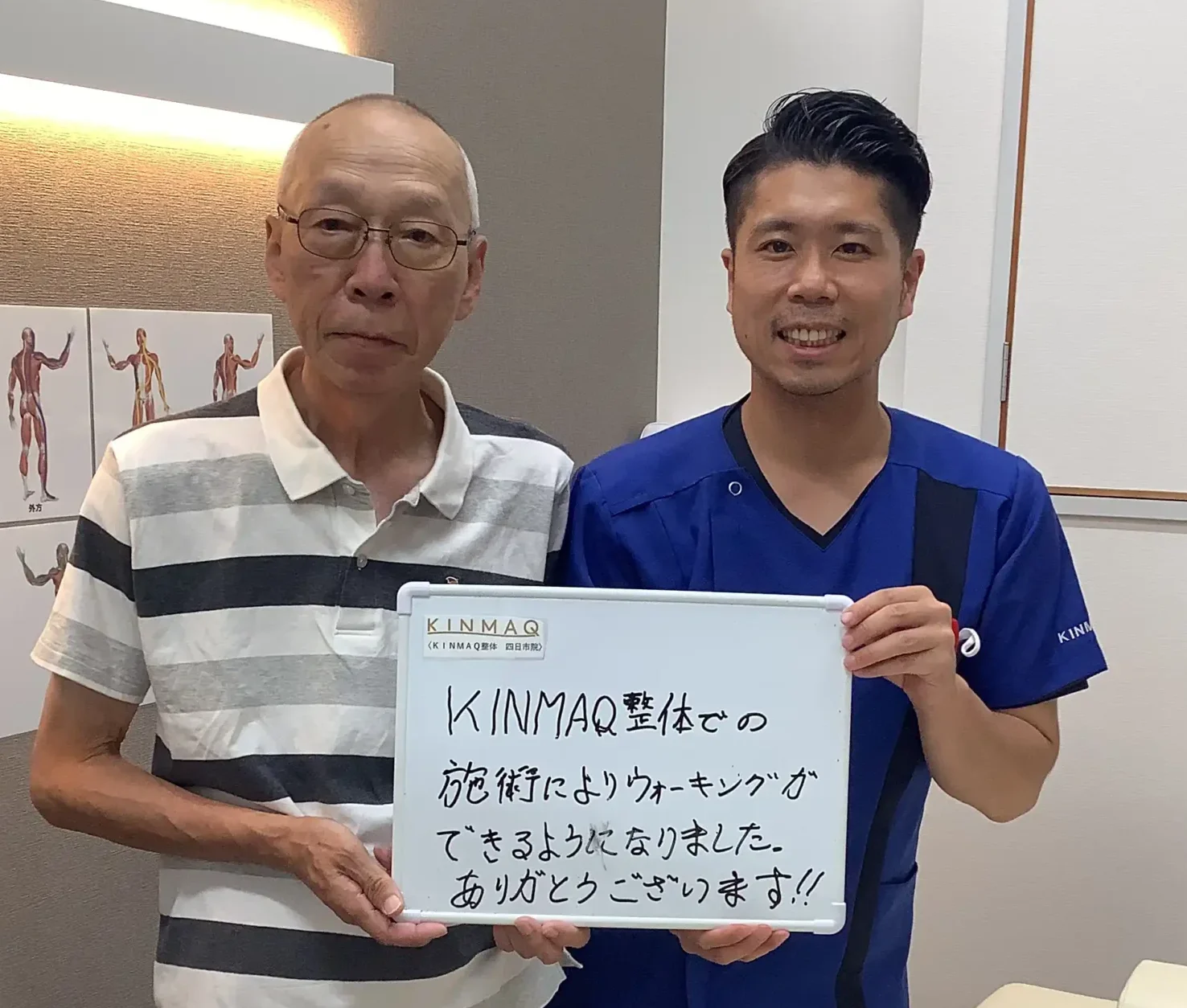 四日市の整体院で腰痛の改善のために通院していた男性の改善実績として。施術後のご本人と担当する理学療法士が一緒に『KINMAQ整体でのせじゅつによりウォーキングができるようになりました。ありがとうございます！！』と書いたホワイトボードを持ち、担当した理学療法士と2ショットを撮影したときの写真。