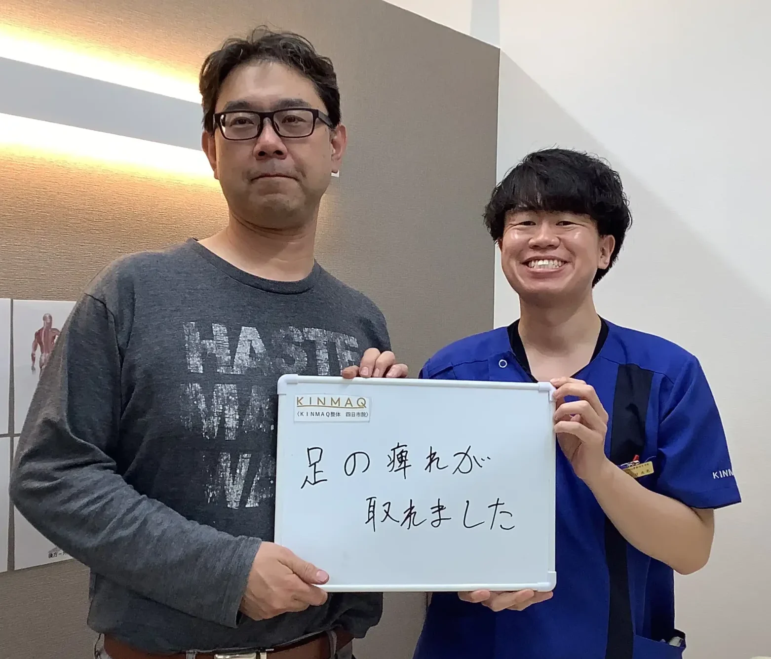 四日市の整体院で坐骨神経痛の改善のために通院していた男性の改善実績として。施術後のご本人と担当する理学療法士が一緒に足の痺れが取れましたと書いたホワイトボードを持ち2ショットを撮影したときの写真。
